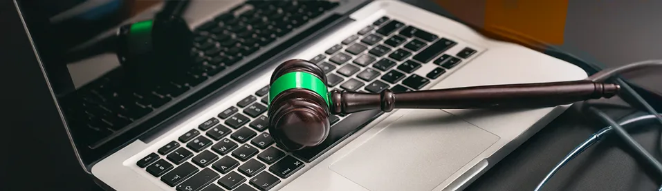 Martelo de juiz de madeira com detalhe verde repousa sobre o teclado de um laptop aberto, simbolizando que a assinatura eletrônica tem validade jurídica.