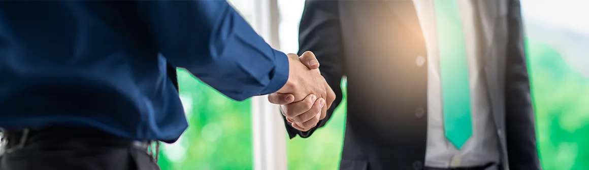 Um aperto de mãos entre dois profissionais em trajes de negócios, simbolizando o sucesso e a consolidação do Programa de parcerias.