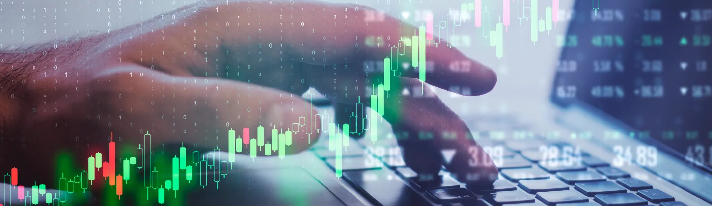 Uma mão digita em um laptop com uma sobreposição digital de gráficos e números do mercado financeiro. A imagem simboliza o monitoramento e a análise de dados essenciais para a estabilidade de uma empresa, que são ações cruciais para um Business Continuity Plan.