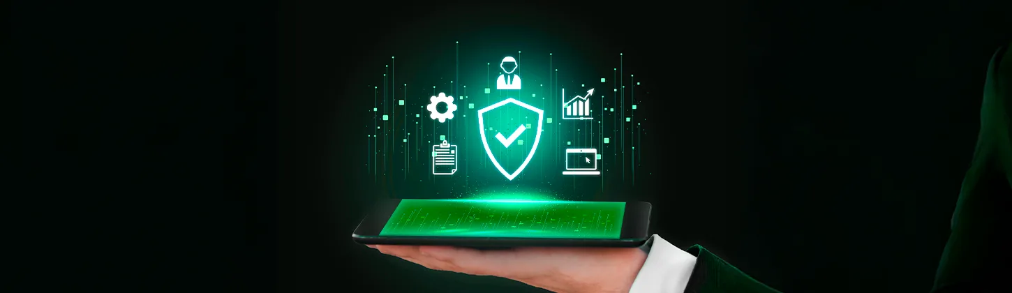 Uma mão segura um tablet com um holograma verde de um escudo e vários ícones de gestão e segurança. A imagem simboliza a conformidade e a segurança digital, em linha com as instruções normativas ITI 2025 e as exigências regulatórias.