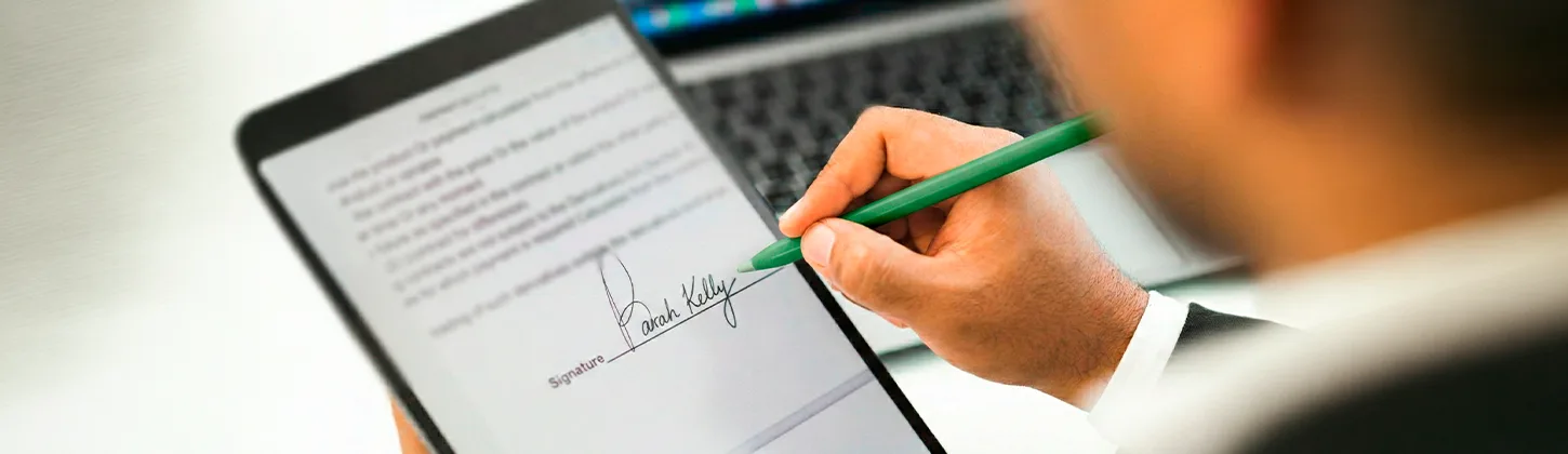Usuário assina documento digital em tablet com caneta verde, ilustrando o controle sobre o redimensionamento do pin de assinatura na tela.