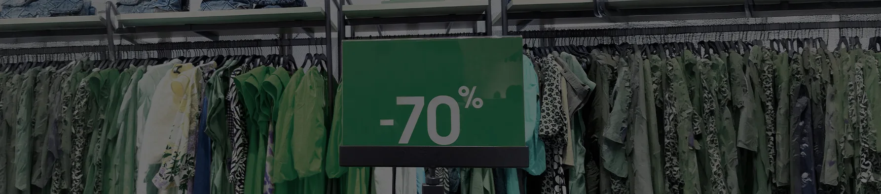 Placa de promoção com "-70%" em destaque em uma arara de roupas, ilustrando as vantagens da assinatura eletrônica no varejo para o setor.