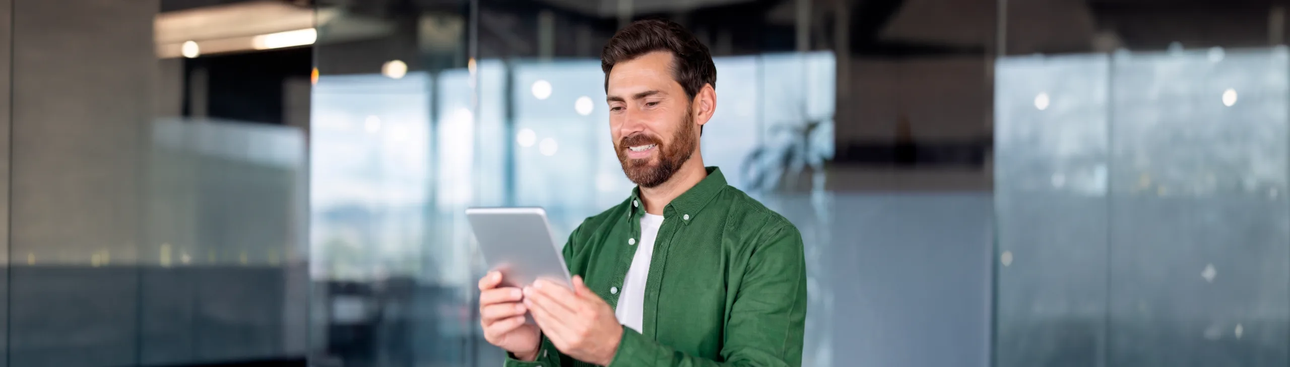 Homem de camisa verde usa tablet em escritório, destacando a praticidade da assinatura eletrônica e digital para autônomos.