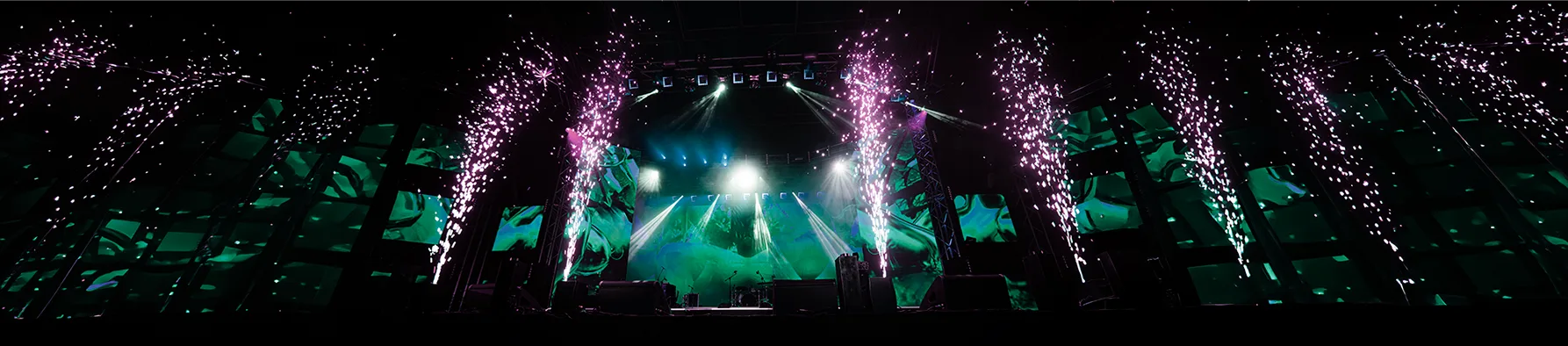 Palco iluminado de show com efeitos pirotécnicos, ilustrando a prevenção de armadilhas contratuais em grandes eventos.